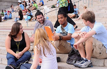 Five students sit on steps, talking
