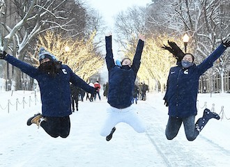 Three students having fun in the snow on campus at Columbia University