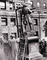 Men maneuver a ladder and crane next to the statue of Alexander Hamilton