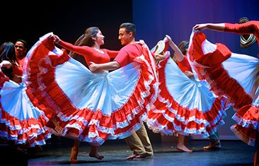Woman in bright red and white dress twirls with a male partner