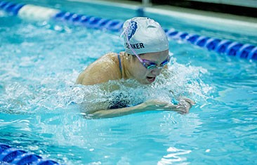 Female swimmer wearing goggles and swim cap does laps