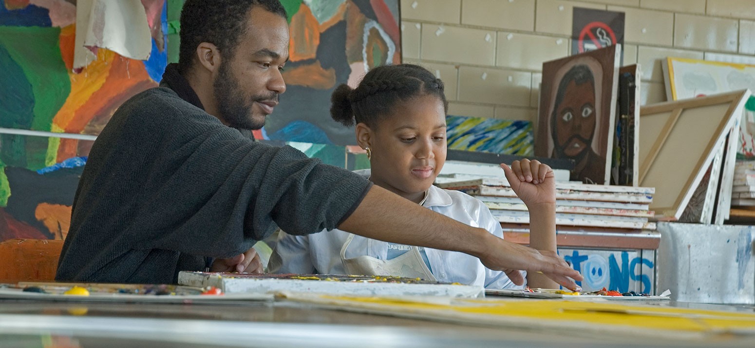 A man helps a young girl with an arts project