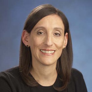 Esta Stecher, a woman with long dark hair, smiling.