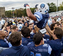 The Columbia Lions football team lifts a teammate into the air in celebration.