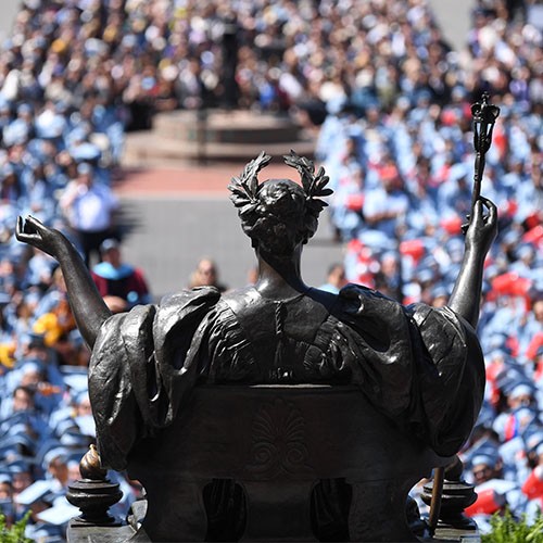 Alma Mater looks over Commencement, a sea of blue gowns. 