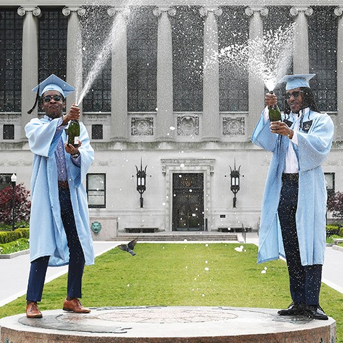 Graduates champagne bottle popping on low steps in cap and gown
