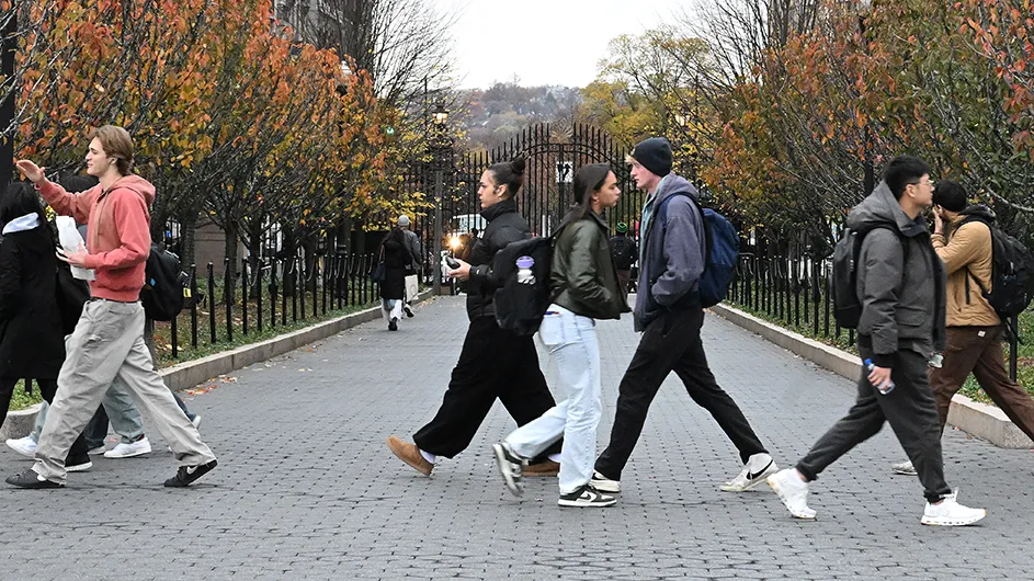 Students walking on Columbia’s Morningside campus with the closed gates in the background.