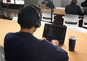 Student types on laptop while wearing headphones.